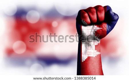 Flag of Cambodia painted on male fist, strength,power,concept of conflict. On a blurred background with a good place for your text.