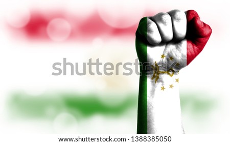 Flag of Tajikistan painted on male fist, strength,power,concept of conflict. On a blurred background with a good place for your text.