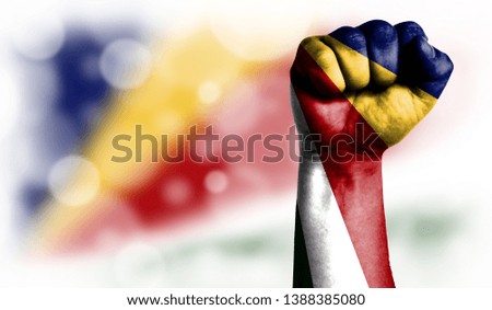Flag of Seychelles painted on male fist, strength,power,concept of conflict. On a blurred background with a good place for your text.