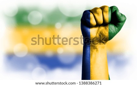Flag of Gabon painted on male fist, strength,power,concept of conflict. On a blurred background with a good place for your text.