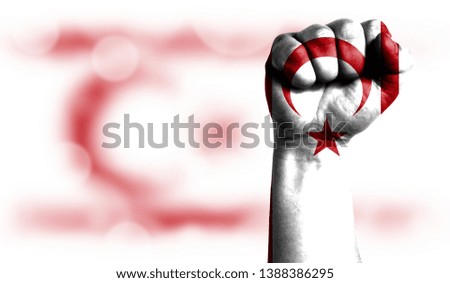 Flag of Turkish Republic of Northern Cyprus painted on male fist, strength,power,concept of conflict. On a blurred background with a good place for your text.