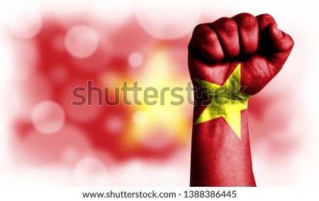 Flag of Vietnam painted on male fist, strength,power,concept of conflict. On a blurred background with a good place for your text.