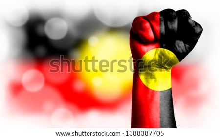 Flag of Australian Aboriginal painted on male fist, strength,power,concept of conflict. On a blurred background with a good place for your text.