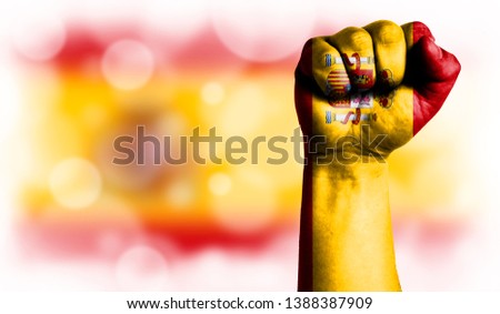 Flag of Spain painted on male fist, strength,power,concept of conflict. On a blurred background with a good place for your text.