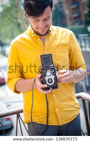 hipster young man with old camera on the balcony
