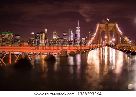 New York city by night over the Brooklyn bridge with an amazing view of the Manhattan skyline illuminated by beautiful city lights