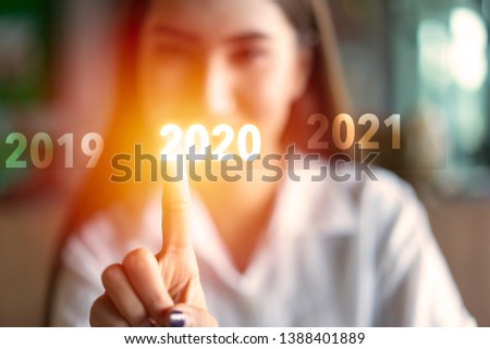 Happy young Asian woman Finger pressing welcome year 2020 start button. Business new year card or celebrate, soft focus picture, Vintage tone, Target Business development to success in 2020 concept.