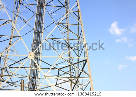 Telecommunications tower, antenna and satellite dish with bright blue sky as a background.
