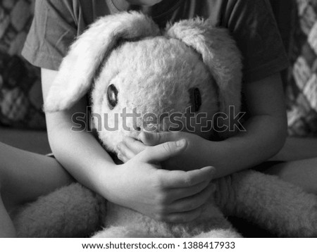Old toy hare in children's hands, black and white, retro