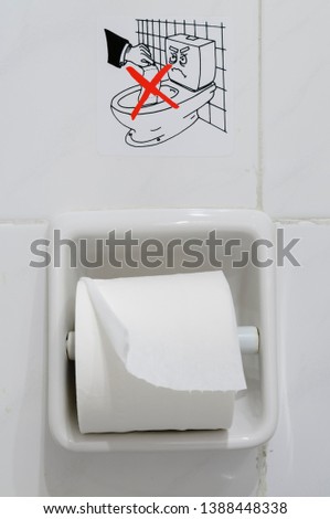 Sign above toilet paper in a hotel, warning guests not to flush toilet paper into the toilet bowl