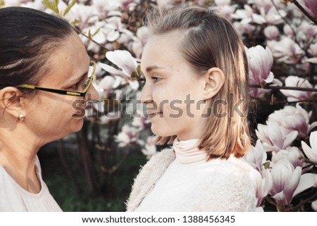 Young beautiful girl with her mother relax in the beautiful garden. Fantastic pink Magnolia