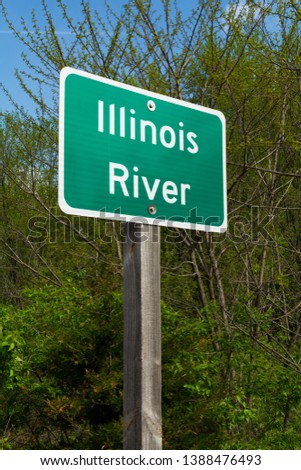 Illinois River street sign with woodland in background.