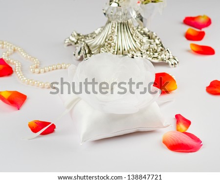 Exquisite pillow for wedding rings on gray background  with rose petals