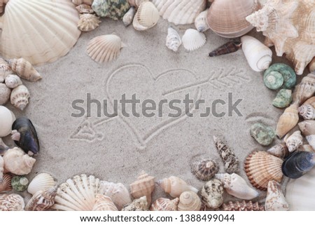 Heart painted on sand, surrounded by seashells, picture with symbols of love.