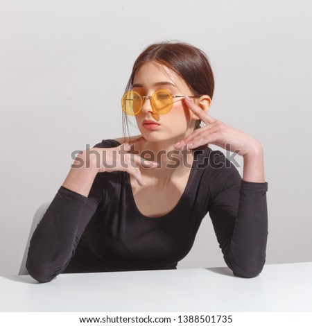 young attractive brunette girl in yellow glasses is sitting at the table.
