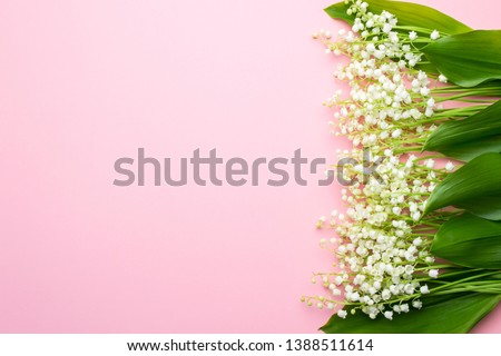 Floral background with lily of the valley flowers. Flat lay, top view, pastel pink background, copy space. Lovely greeting card with lily of the valley for Mothers day, wedding or birthday.