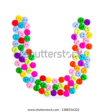 Letter U of the English alphabet from a group of colorful small buttons on a white background