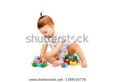 Cute happy baby playing with developmental wooden toy on white background. Picture of curious baby.