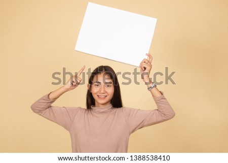 Young Asian woman point to blank sign  on beige background