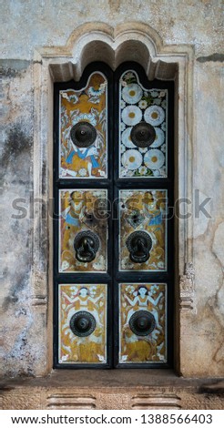 The old two-fold doors with drawings on religious subject conducting in one of Buddhist temples on the island of Sri Lanka.