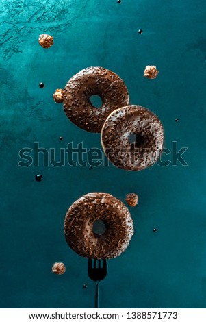 Flying donuts with chocolate glazed, sprinkled nuts on a dark blue background. Sweet food concept. Promo flyer donut with copy space. levitation food