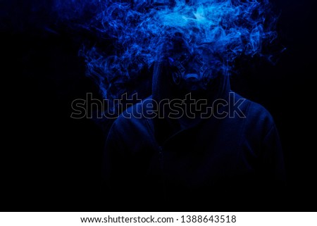 Man smoking an electronic cigarette on the dark background with gas mask on face