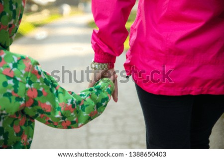 A cute picture of a young mother and a toddler holding hands.Concept.-Inseparable Love Connection Throughout Your Life.-Image