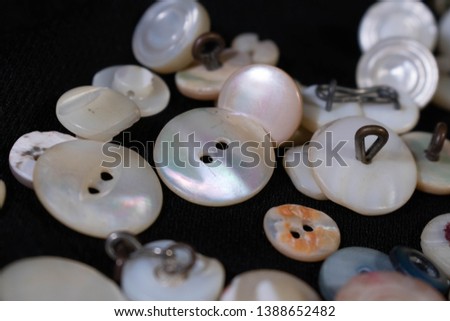 A close up view of several buttons made of Mother of Pearl on a black background.