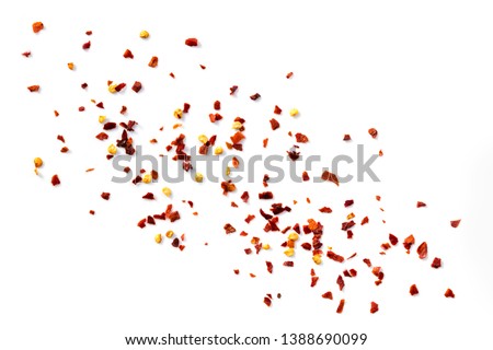 Hot chilli flakes scattered over white background, top view. Royalty-Free Stock Photo #1388690099