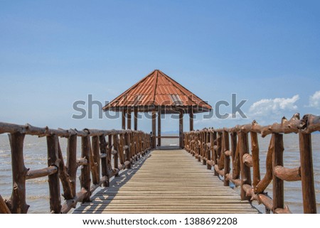 Beautiful seascape picture a wooden bridge extends to the sea pavilion at beach with clouds and sky,