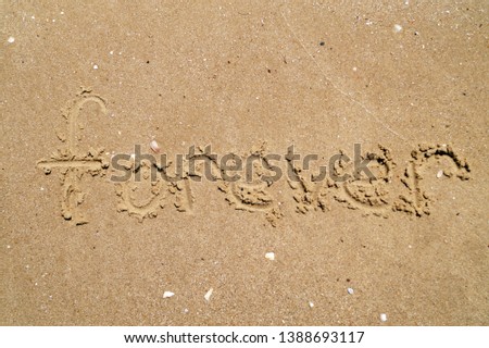 Word Forever written on wet sand. Summer beach background, sea vacation.