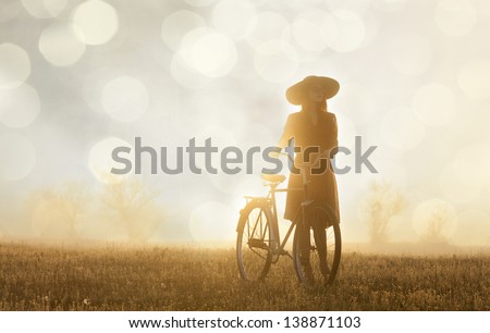 Girl and on a bike in the countryside in sunrise time Royalty-Free Stock Photo #138871103