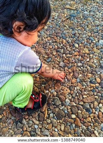 toddler playing picking up river stone,marble rock for outdoor activity. let them be free and use their imaginary to play stock photo -image
