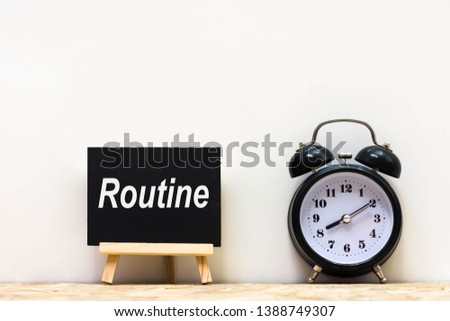 Alarm clock and daily routine words blackboard on desk white background.   Chalkboard write routine text on table for copy space.  Royalty-Free Stock Photo #1388749307