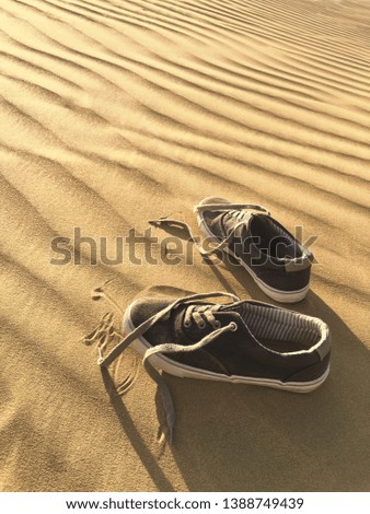 A pair of shoes left in the stark desert sand dunes. Concept for experience the nature closely.