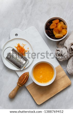 Fresh Orange Juice and Peel, raisins, dried apricots, almonds on marble backround with copy space