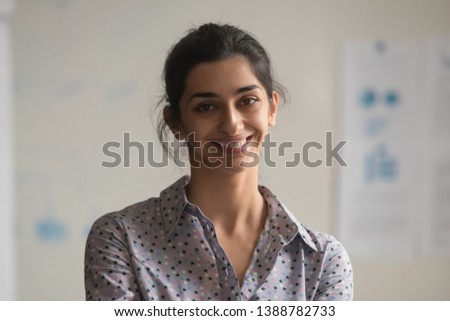 Headshot portrait of smiling attractive indian female employee look at camera making picture in office, happy positive ethnic woman beautiful millennial worker posing for photo at workplace