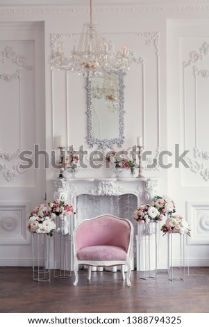 Elegant white fireplace full of flowers. Elegant white room decorated with easel and hat boxes. Wedding decorated area. Vintage decor in light interior 