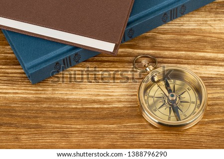 Compass on wooden background with vintage book, concept for direction transportation and travel, with copy space