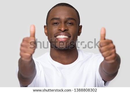 African man with ultra white smile looking at camera showing thumbs up giving best recommendations dental clinic, teeth whitening dental industry advertisement, concept image on grey background blank