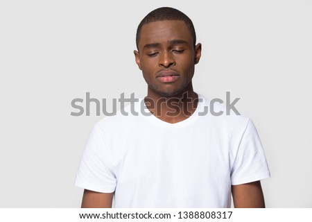 Head shot studio portrait over grey blank isolated dark-skinned sad man wearing white t-shirt feels frustrated and unhappy having broken heart personal problems, desperate guy misunderstanding concept Royalty-Free Stock Photo #1388808317