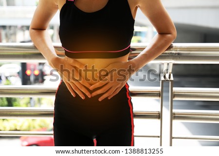 Female athletes, abdominal pain, menstrual period during exercise on walking street in the city. Royalty-Free Stock Photo #1388813255