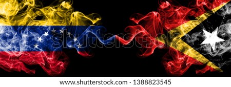 Venezuela vs East Timor smoky mystic flags placed side by side. Thick colored silky smoke flags of Venezuela and East Timor.
