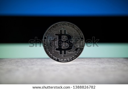 Physical silver version of Bitcoin (BTC) and Estonia Flag on the background. Conceptual image for investors in cryptocurrency and Blockchain Technology.