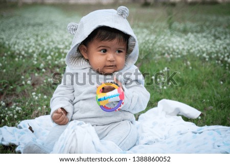 Cute little asina baby sitting at white flower garden