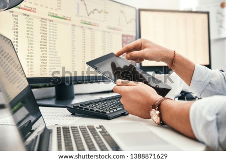 Modern businessman. Cropped photo of young trader in formal wear and watch on his hand using digital tablet and analyzing data while working in his office.