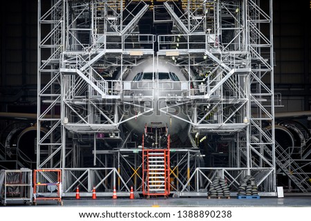  Aircraft push back into the maintenance area.Airplane parking in hangar for maintenance service check by aircraft technician.Aircraft Docking and Maintenance Platforms in front of airplane. Royalty-Free Stock Photo #1388890238