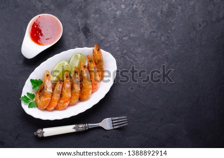 Large fried shrimp with citrus and tomato sauce on a slate background. Selective focus.