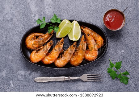 Large fried shrimp with citrus and tomato sauce on a slate background. Selective focus.