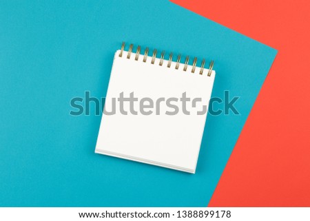 open notebook on two-color background blue and coral pink, top view, spiral notepad with blank sheet on the table flat lay